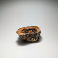 A small rustic wooden bowl or dish made from a natural wood slice with visible grain and bark, photographed on a clean light gray to white studio background.